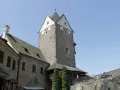Kamienny zamek Loket z wieżą i budynkami mieszkalnymi pod błękitnym niebem.