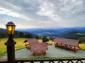 Widok z **schroniska górskiego Orzeł** na malownicze wzgórza. Wiaty z ławami i stołami zapraszają do odpoczynku.