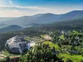 Malownicze Karkonosze latem: rozległy kompleks hotelowy otoczony zielenią, z widokiem na góry i miasteczko. Idealne miejsce na wypoczynek i odkrywanie atrakcji.