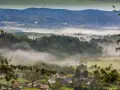 Mgliste poranki nad Sudetami. W oddali widać zamek, a niżej rozciągają się lasy i urokliwe miejscowości.