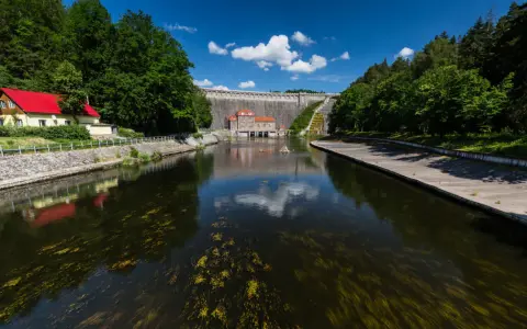 Zapora Pilchowice trasa. Malownicza droga nad zbiornikiem wodnym, z widokiem na monumentalną budowlę i otaczającą zieleń.