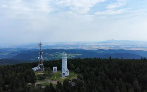 Wieża widokowa niczym wielka sowa, ile się wchodzi, góruje nad lasem. Obok maszt telekomunikacyjny.
