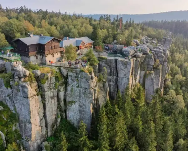 Schronisko w Górach Sowich na skalnym urwisku, otoczone lasem.