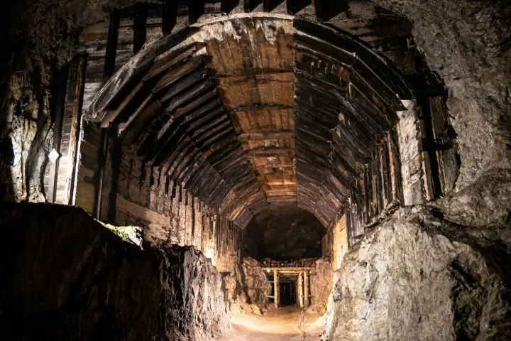 Wnętrze tunelu w kompleksie Riese, gdzie kryją się tajemnice wojny. Drewniane wsporniki i skalne ściany tworzą mroczny korytarz.