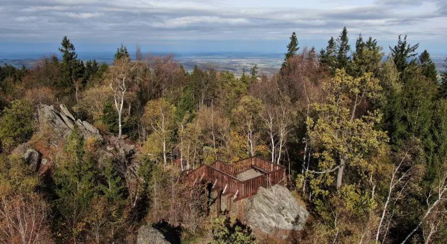 Drewniana platforma widokowa na skalistym okole szczyt. Jesienne drzewa i daleki krajobraz pod chmurami.