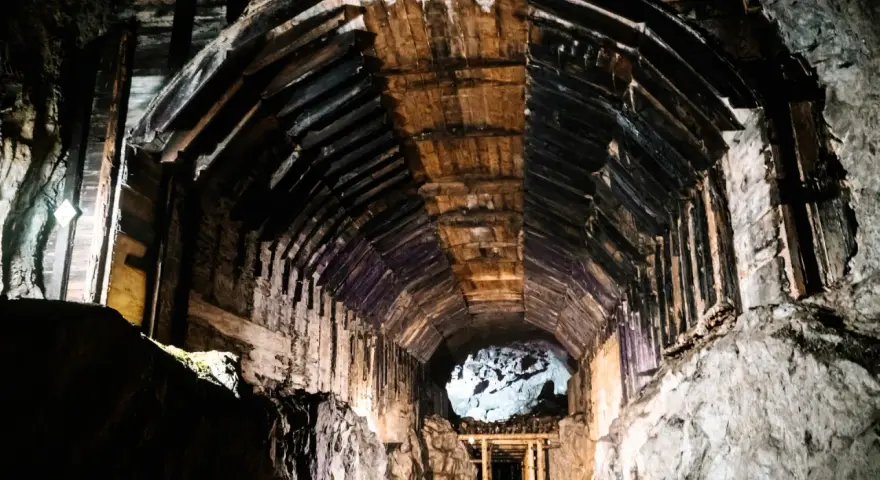 Wnętrze kopalni, drewniane wsporniki tworzą tunel, który prowadzi do jasnego otworu. To część kompleksu Rize.