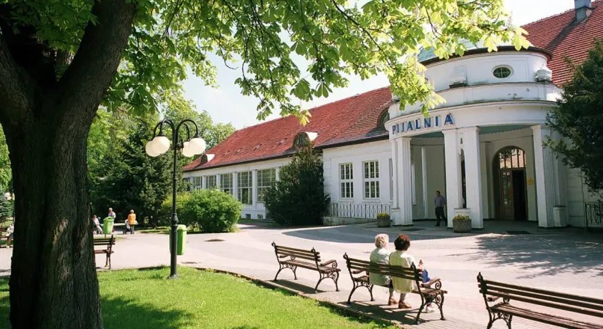 Uzdrowiska na Dolnym Śląsku: Pijalnia wód w otoczeniu zieleni, z ławkami dla kuracjuszy.