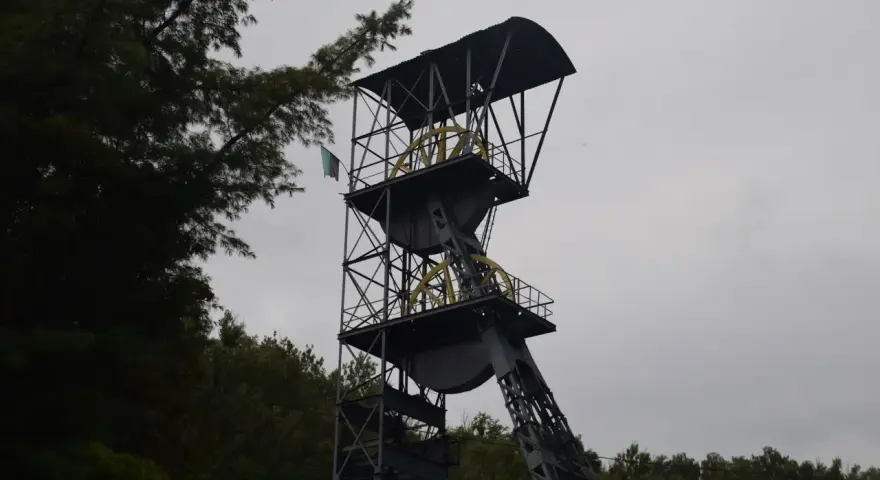 Wieża szybu kopalnianego, jedna z atrakcji Nowej Rudy, z flagą powiewającą na wietrze.