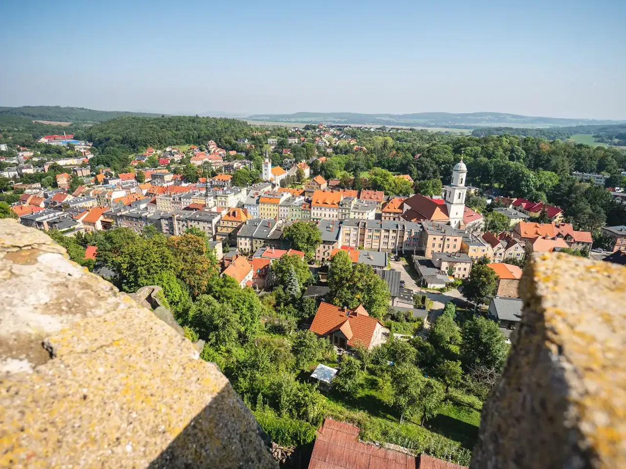 Widok z mur&oacute;w zamku Bolk&oacute;w na urokliwe miasteczko z czerwonymi dachami i zielonymi wzg&oacute;rzami w tle.